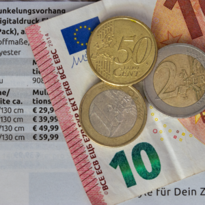 Euro coins and bills on a price list, symbolizing finance and economy.