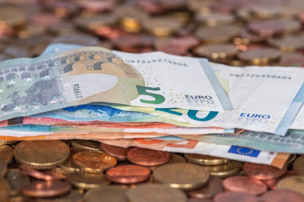 Stack of euro banknotes and scattered coins symbolizing wealth and finance.