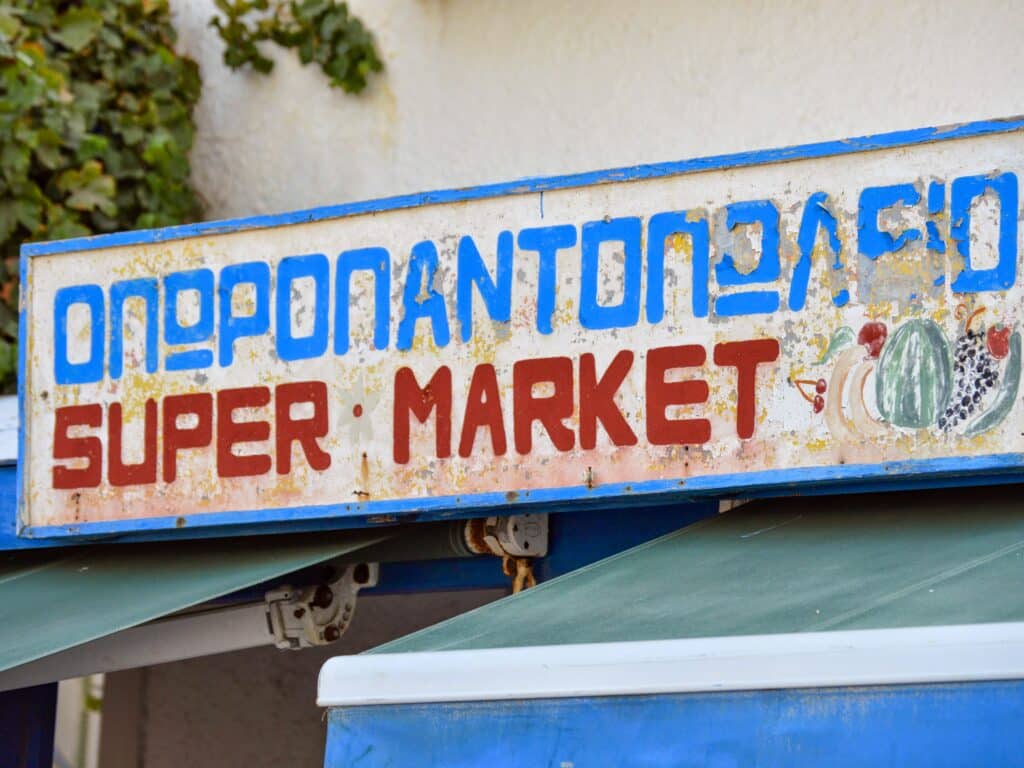 Enseigne devant un supermarché grec pour faire ses courses au meilleur prix.