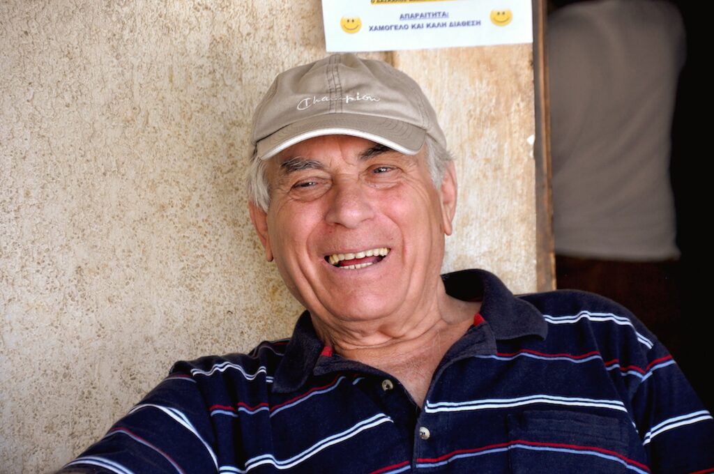 A cheerful elderly man posing outdoors on Naxos, Greece, exuding warmth and authenticity.
