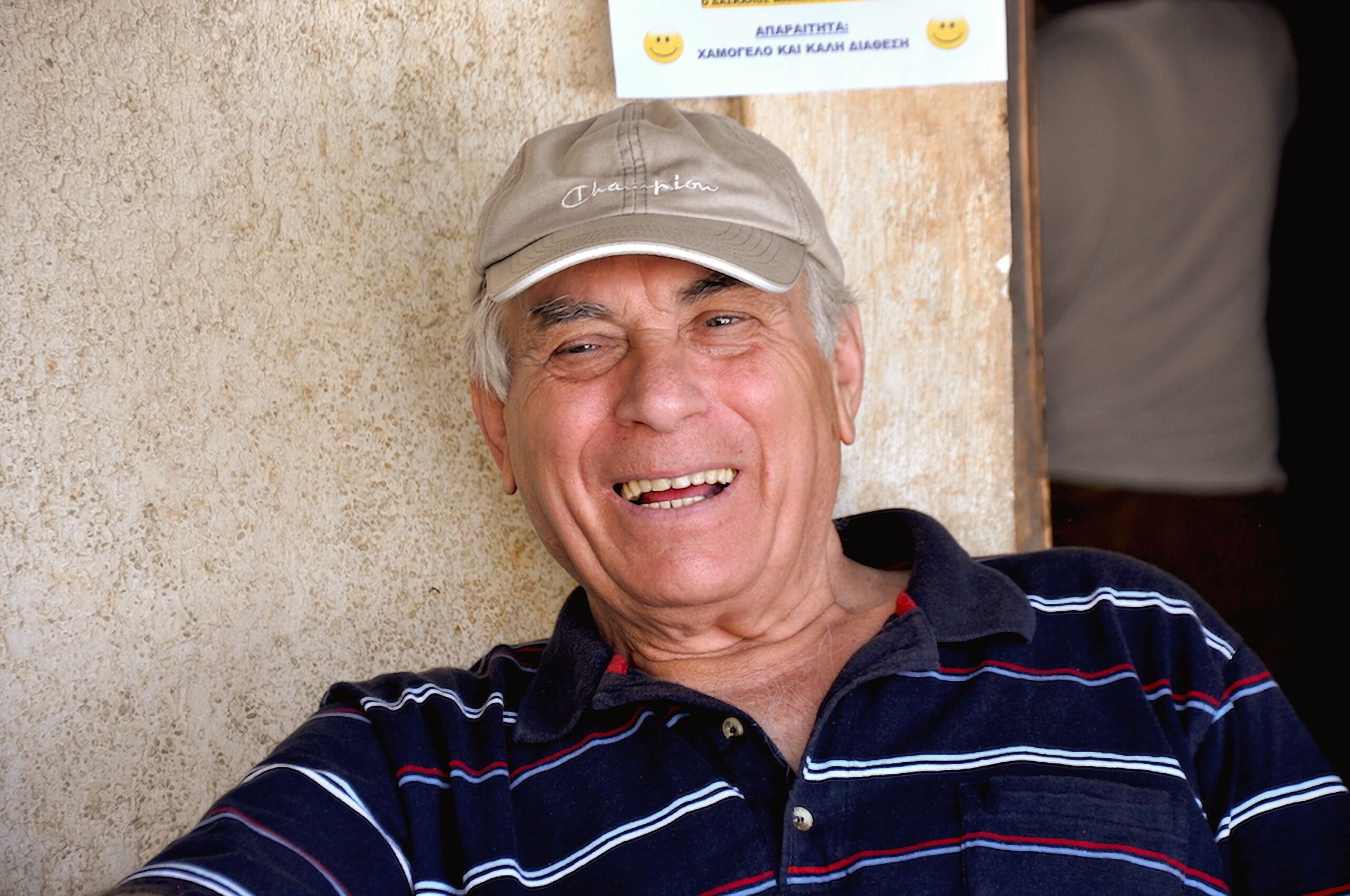 A cheerful elderly man posing outdoors on Naxos, Greece, exuding warmth and authenticity.