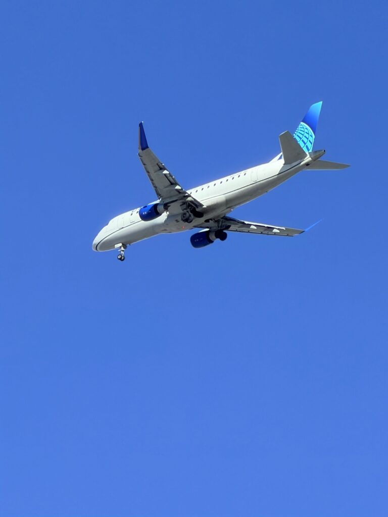 A commercial airplane flying through a clear blue sky, showcasing travel and aviation.